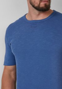 Blauw T-shirt met korte mouwen van zacht, gestructureerd materiaal. Heeft een ronde hals en een subtiele heathered patroon. Slim-fit ontwerp.