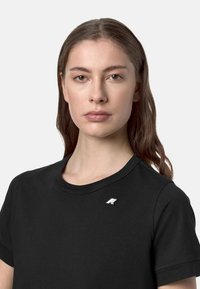 T-shirt nera a girocollo con maniche corte, caratterizzata da un piccolo logo argentato sul lato sinistro del petto. Tessuto con una morbida trama.
