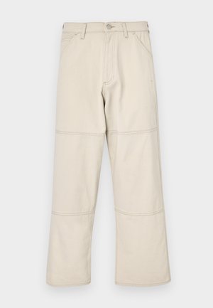 Bež traperice širokog kroja izrađene od pamuka s glatkom teksturom, s trostrukim šavovima i pet džepova uključujući džep za novčiće.