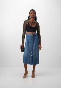 Jeans midi kjol med sex knappar fram, blåtvätt, rak skärning, i kombination med en svart kort topp och transparenta blockklack sandaler.