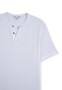 Maglietta bianca a maniche corte con collo henley, due bottoni neri e una texture morbida. L'etichetta visibile all'interno del colletto riporta "CALLIOPE L."