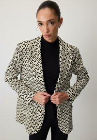Blazer într-un model geometric crem și negru, cu rever tăiat, mâneci lungi și o croială ajustată, având un material negru contrastant dedesubt.
