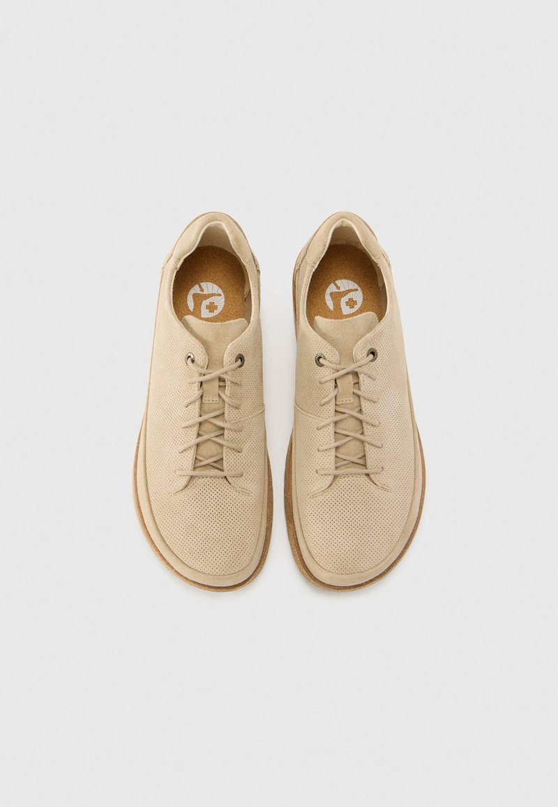 Ein Paar beiger, perforierter Wildleder-Schnürschuhe mit hellbraunen Sohlen, von oben auf einem weißen Hintergrund betrachtet.