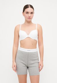 Sutiã moldado branco e calções de algodão cinza com uma faixa branca da Calvin Klein. Apresenta um tecido suave e um design ajustado.