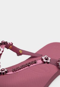 Ροζ σαγιονάρα με μεταλλικές διακοσμήσεις σε σχήμα λουλουδιού και λογότυπο "havaianas" σε υφασμένο πέλμα και λουράκια.