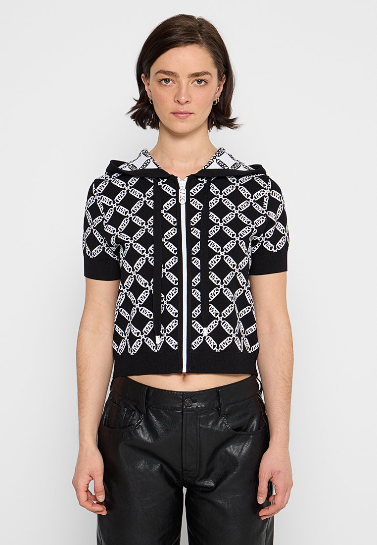 Korte zwarte hoodie met een wit geometrisch patroon, korte mouwen en een ritssluiting aan de voorkant. Beschikt over een capuchon met trekkoord en een zachte textuur.