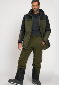 Completo da sci isolato da uomo con giacca bicolore in verde scuro e nero, e pantaloni abbinati con sezioni inferiori e tasche nere.