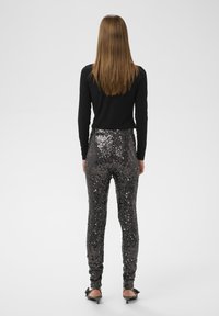 Visokorazdvojene hlače s bleščicami v temno sivi barvi z oprijetim krojem, ki se ponašajo z sijajno teksturo in subtilnimi navpičnimi črtami.