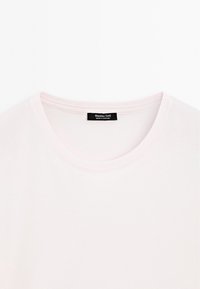 Light pink, short-sleeve t-shirt with a rounded neckline. Features a black label with "Massimo Dutti" and "Made in Portugal" inside. Smooth texture.