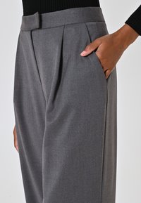 Grijze op maat gemaakte broeken met een hoge taille, geplooide voorkant en zijzak. Gemaakt van een zachte, gestructureerde stof voor comfort en stijl.