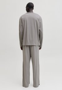 Un haut gris à manches longues et un pantalon large assorti, fabriqués en tissu doux. Le haut a un col rond et une coupe décontractée, avec des coutures minimales.