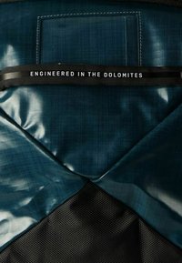 Tessuto blu scuro con finitura lucida, rete nera testurizzata e un'etichetta che riporta "INGEGNERIZZATO NELLE DOLOMITI" in lettere bianche.