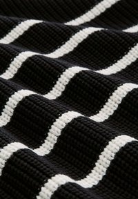 Teksturna tkanina z black ozadjem in belimi zigzag črtami, ki prikazuje tkano zasnovo s poudarjenimi linijami in kontrastnimi barvami.