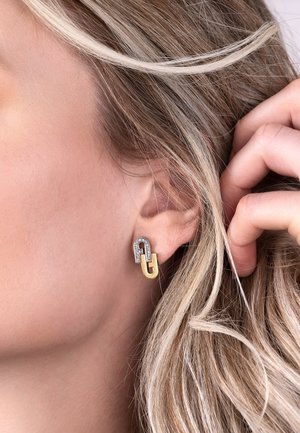 Gold and silver earrings featuring a chain link design with diamond accents. Smooth, polished texture; modern shape.