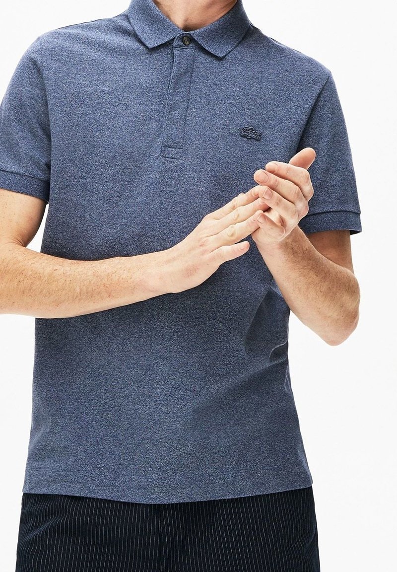 Námořnická modrá polo tričko s krátkým rukávem, texturovaná tkanina, klopa na dva knoflíky a vyšívané logo na hrudi. Lehce přiléhavý střih.