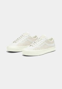 Hvide kanvas sneakers med en tekstureret, vævet overdel, der har en lav profil, rund tå og flade snørebånd over en polstret sål.