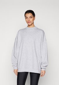 Sudadera gris de gran tamaño con cuello alto, puños acanalados y un corte relajado, hecha de una suave tela de mezcla de algodón texturizada.