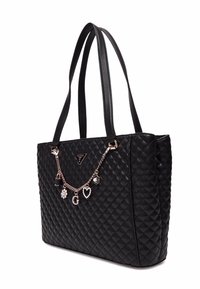 Borsa a tote nera trapuntata con manici in pelle liscia. Presenta una catena decorativa con ciondoli, tra cui un lucchetto, un fiore e cuori.