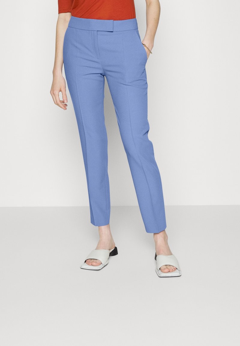 Ljusblå skräddarsydda byxor med slim fit, med slät framdel, bälteshällor och sidofickor, i kombination med ljusgrå slip-on skor.