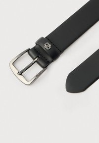 Schwarzer Ledergürtel mit einer silbernen Metallschnalle. Der Gürtel hat eine glatte Textur und ein verjüngtes Ende, mit einem in der Nähe der Schnalle eingeprägten Logo.