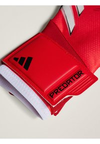 Guanti da portiere rossi con una presa strutturata, un cinturino per il polso imbottito con il testo nero "PREDATOR" e dettagli in elastico bianco sul polsino.