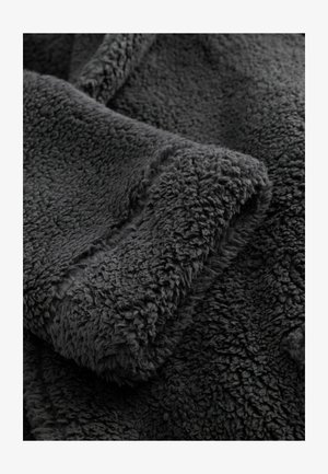 Grau Fleece-Stoff mit einer weichen, strukturierten Oberfläche. Das Material wirkt dick und plüschig, mit einem leichten Glanz und einem unregelmäßigen, flauschigen Muster.