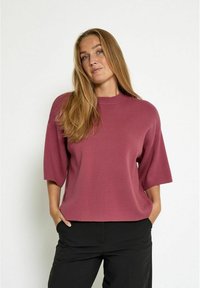 Short-sleeve sweater in mauve, featuring a round neckline and soft texture. Loose fit, with a straight hemline and minimal design details.