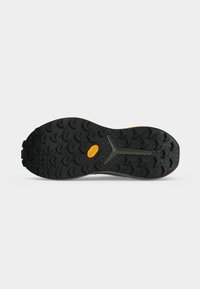 Semelle noire de sneaker avec un motif de bande de roulement rugueux et un design central en forme de Y vert, avec un logo Vibram jaune près du centre.