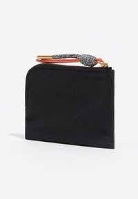 Czarna prostokątna saszetka na zamek błyskawiczny ze złotym zamkiem oraz czarno-białą pętelką sznurkową przymocowaną do pomarańczowego paska.