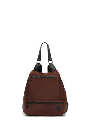 Brown nylon backpack with black straps, featuring two zippered front pockets and a circular logo on the lower front. Smooth texture and structured shape.