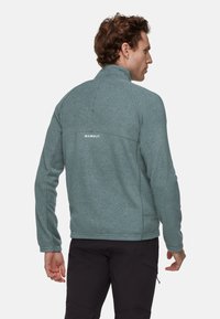 Giacca in fleece azzurro chiaro con colletto alto, dotata di chiusura con zip e logo ricamato sulla schiena. Design con cucitura continua sulle spalle.