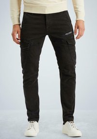 Schwarze Baumwollmischung Cargo-Hosen mit mehreren Taschen, slim-fit Design, verstärkten Nähten und einer strukturierten Oberfläche. Kombiniert mit weißen Sneakers.