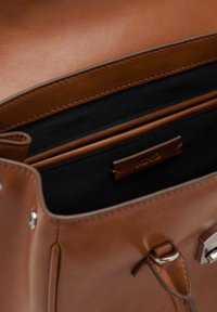 Bruine nepleren handtas met een gladde afwerking, voorzien van een zwarte stoffen interieur, meerdere vakken en accenten in zilverkleurige hardware.