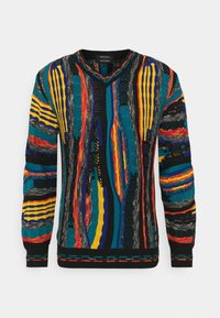 Monivärinen neulepusero, jossa on V-kaula-aukko, teksturoituja kuvioita turkoosissa, mustassa, oranssissa, keltaisessa ja punaisessa, sekä resorikujat ja helma.