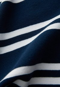 Tissu bleu marine avec des rayures horizontales blanches, présentant un tissage texturé qui lui confère une apparence structurée. Les rayures varient en largeur.