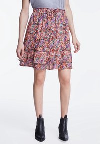 Jupe mini à motifs floraux avec taille froncée, dégradé de couleurs roses, oranges et violettes. Présente un ourlet froncé et un tissu léger.