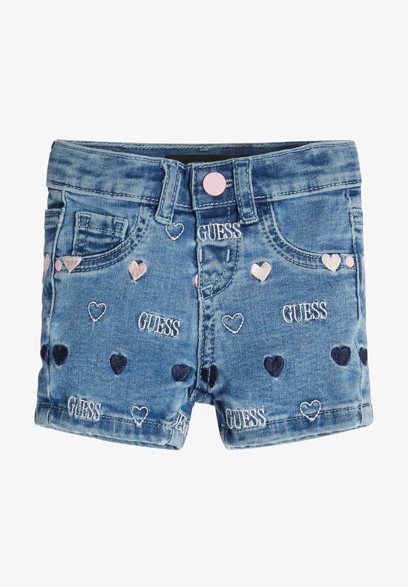 Shorts en denim pour tout-petit avec bouton rose, poches avant, cœurs brodés en rose et bleu marine, et plusieurs logos "GUESS" blancs sur le tissu.