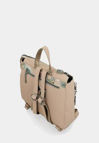 Mochila de cuero beige con ribete de patrón floral, bolsillo frontal con cremallera, correas ajustables y asa superior, mostrada en un ligero ángulo sobre un fondo blanco.