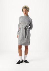 Pilkas suknelė ilgomis rankovėmis, su imitaciniu kaklu, juosmens diržu ir kelių ilgio apvadu. Audinys atrodo minkštas, su švelniu heathered tekstūra.