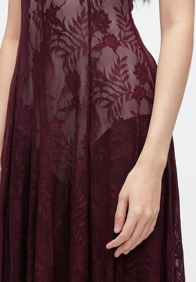 Bordové čipkované šaty s kvetinovými vzormi, polopriesvitnou textúrou a splývavou siluetou, s priliehavým živôtikom a rozšírenou sukňou.