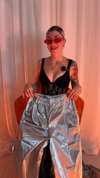 Ασημί αντανακλαστικό παντελόνι με ελαστική μέση, που φέρει το λογότυπο της Adidas. Το μοντέλο φοράει μαύρο τοπ από δαντέλα και κόκκινα γυαλιά ηλίου.