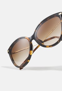 Ochelari de soare cu imprimeu țestoasă, cu lentile supradimensionate, rotunde. Nuantă bronz cu gradient, accente din metal auriu și un finisaj lucios, elegant.