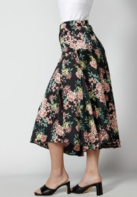 Kuvioitu kukkakuosinen hame mustalla taustalla, jossa vaaleanpunaisia ja vihreitä kukkia, liehukehelmainen malli ja joustava vyötärönauha. Yhdistetty mustien korollisten mules-kenkien kanssa.