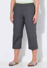 Grijze cropped broeken met een elastische tailleband, voorzien van zijzakken en een soepele textuur. Gecombineerd met lichtgrijze slippers.