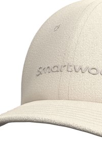 Gorra beige clara con una tela texturada y un visera ligeramente curvada. El logotipo "smartwool" aparece en letras en relieve en la parte frontal.