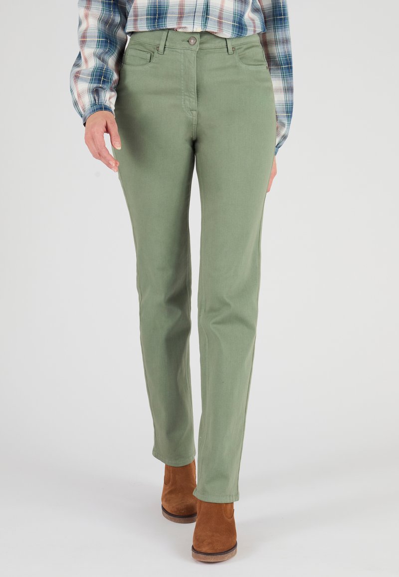 Pantaloni di cotone verdi con una vestibilità slim, dotati di chiusura a bottone e tasche frontali, abbinati a stivali alla caviglia in camoscio marrone.