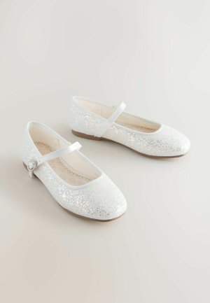 Ballerines blanches pailletées avec un bout arrondi, un petit talon et une sangle décorative avec un accent argenté. Texture lisse, finition scintillante.