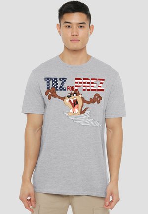 Young man wearing gray T-shirt with cartoon Tasmanian Devil emerging from a tornado and text "Taz for Prez" in red, white, and blue letters.