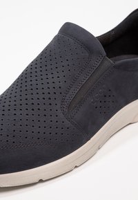 Sötétkék, átlátszó bőr slip-on cipő, gumi talppal. Rugalmas oldalsó panelekkel és diszkrét logó részletekkel rendelkezik. Sima textúrával.