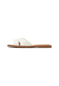 Flad sandal med brede hvide læder krydspatenter og en brunt træsål, set fra siden på en hvid baggrund.